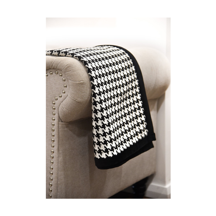 The Classic Elegance Houndstooth Throw elegantly folded on an armchair