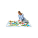 Infant joyfully playing on the colourful Tiny Love Meadow Days Super Mat filled with engaging activities