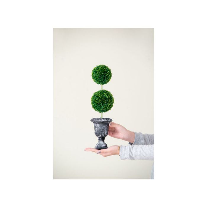 Artificial topiary in a vase beside a window, creating a serene and welcoming vibe